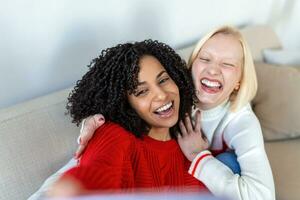 Shot of a two female friends taking selfie in the apartment. My roomies. Shot of two young women taking a selfie while sitting at home. Shared Living roommates make a selfie photo