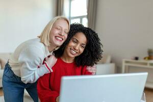 Two beautiful women using laptop for an online video call and online toasting with their friends. Online party for friends. photo