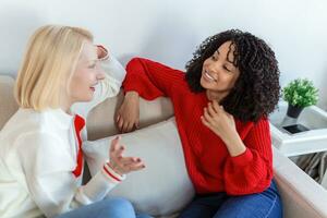 Two female friends sitting on sofa. Best friends having coffee together on sofa at home photo