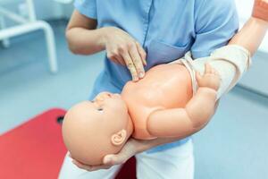 Woman performing CPR on baby training doll with one hand compression. First Aid Training - Cardiopulmonary resuscitation. First aid course on cpr dummy. photo