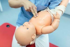 mujer ejecutando cpr en bebé formación muñeca con uno mano compresión. primero ayuda formación - cardiopulmonar resucitación. primero ayuda curso en cpr ficticio. foto