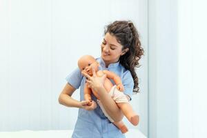 CPR practitioner examining airway passages on infant dummy. Model dummy lays on table and two doctors practice first aid. photo