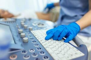 In the Hospital, Obstetrician Pushes Buttons on a Control Panel Before Starting Ultrasound Sonogram Procedure photo