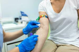 Medical technologist doing a blood draw services for patient. lab assistant with sterile rubber gloves taking blood sample from patient. photo