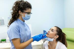 Medical worker wearing personal protective equipment doing corona virus swab on female patient - Covid19 test and health care concept photo