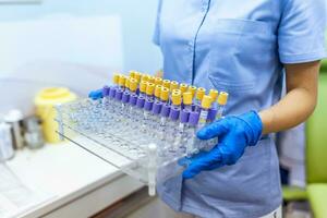 Technician holding blood tube test in the research laboratory. Coronavirus testing. Doctor taking a blood sample tube from a rack in the lab photo