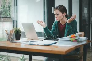 Serious focused woman looking at laptop screen, touching chin, sitting at desk, home office, thoughtful businesswoman pondering strategy, working on online project, searching information photo