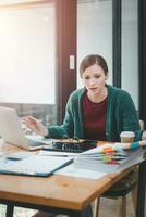 Serious focused woman looking at laptop screen, touching chin, sitting at desk, home office, thoughtful businesswoman pondering strategy, working on online project, searching information photo