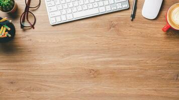 Top view, Wooden Office desk with keyboard computer, cup of coffee, pen, mouse and eyeglass, copy space, Mock up.. photo