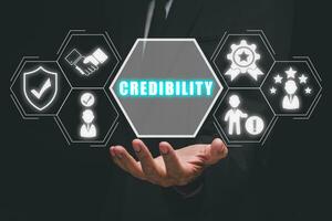 Corporate credibility improvement concept, Business person hand holding credibility icon on virtual screen. photo