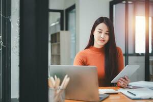 Serious focused woman looking at laptop screen, touching chin, sitting at desk, home office, thoughtful businesswoman pondering strategy, working on online project, searching information photo