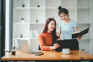 dos mujer de negocios trabajando juntos en digital tableta. creativo hembra ejecutivos reunión en un oficina utilizando digital tableta y sonriente. foto