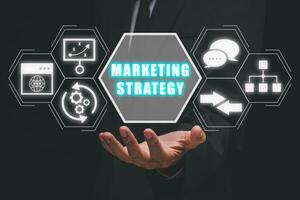 Marketing strategy concept, Businessman hand holding marketing strategy icon on virtual screen. photo