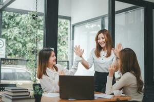 Business team giving a high five to female colleague in meeting. Business professionals high five during a meeting in boardroom. photo