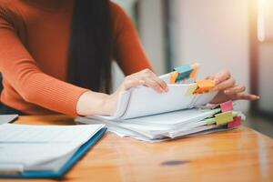 Businesswoman hands working in Stacks of paper files for searching and checking unfinished document achieves on folders papers at busy work desk office photo