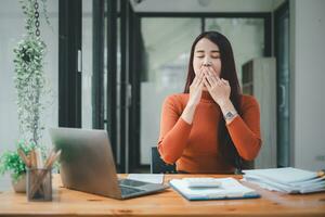 Bored businesswoman yawning at workplace feeling no motivation or lack of sleep tired of boring office routine. photo