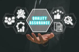 Quality assurance concept, Businessman hand holding quality assurance icon on cirtual screen. photo