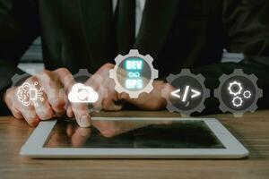 devops concepto, hombre mano conmovedor tableta con devops icono en vr pantalla en escritorio, metodología desarrollo operaciones ágil programación tecnología.concepto. foto