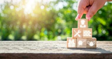 Construction concept, Man hand holding wooden cube block with construction icon with copy space, blueprint and building model. Construction concept. photo