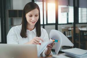 Businesswoman working in Stacks of paper files for searching and checking unfinished document achieves on folders papers at busy work desk office photo