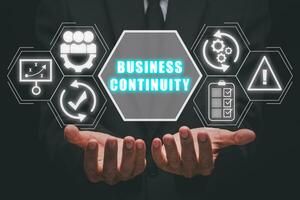 Business continuity concept, Businessman hand holding business continuity icon on virtual screen. photo