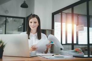 Businesswoman working in Stacks of paper files for searching and checking unfinished document achieves on folders papers at busy work desk office photo