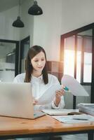 Businesswoman working in Stacks of paper files for searching and checking unfinished document achieves on folders papers at busy work desk office photo