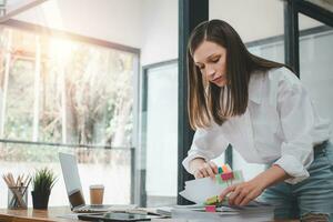 Businesswoman working in Stacks of paper files for searching and checking unfinished document achieves on folders papers at busy work desk office photo