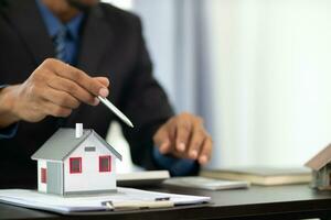 The real estate agent is reviewing the documents and calculating the interest rate to inform the tenant of the monthly installments to be paid before the real estate purchase agreement is finalized. photo