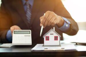 The real estate agent is reviewing the documents and calculating the interest rate to inform the tenant of the monthly installments to be paid before the real estate purchase agreement is finalized. photo