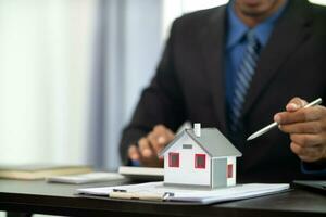 The real estate agent is reviewing the documents and calculating the interest rate to inform the tenant of the monthly installments to be paid before the real estate purchase agreement is finalized. photo