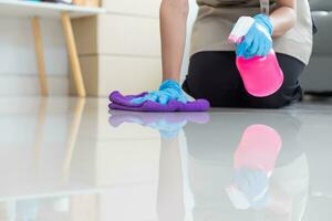 Cleaning staff is wiping cloth with cleaner and disinfectant on the surface of floor to make the floor clean with cleaning products and free from germs clinging to surface of the floor in living room. photo