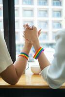 lgbt Q couple wore rainbow wristbands symbolizing lgbt Q group and held hands to show love, friendship and kindness. And lgbt Q couple also promised to love each other forever. Copy space for text photo