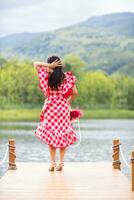 old woman stand on walkway by reservoir watching beautiful scenery of reservoir alone in the evening. back of old woman stand by reservoir alone in evening and with copy space for text. photo