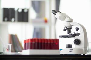 Test tubes and microscope are placed on white table in  lab to prepare virologists who want to use lab to examine samples of virus they received from epidemic. Medical equipment for use in laboratorie photo