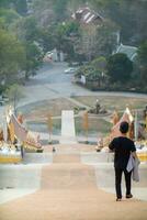 back of young man walking down stairs along corridor to reach his desired destination after walking up stairs to pay homage to Buddha image according to belief and power of Buddhism. photo