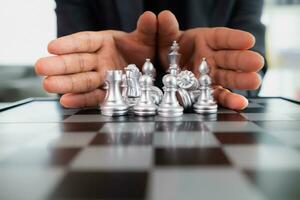 Young businessman planning winning chess move in game of chess representing successful and victorious business path. chess concept representing strategic business strategy to achieve victory. photo