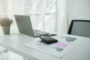 Calculators and Notebook computers are placed on desks in office to prepare accountants to calculate income and expenses to get accurate results and use calculators review company investment profits. photo