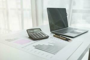 Calculators and Notebook computers are placed on desks in office to prepare accountants to calculate income and expenses to get accurate results and use calculators review company investment profits. photo