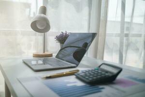 Calculators and Notebook computers are placed on desks in office to prepare accountants to calculate income and expenses to get accurate results and use calculators review company investment profits. photo