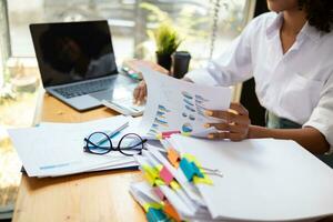 secretary searches through stacked documents on desk in office to find lease within stacked documents just before meeting. concept difficulty in finding hire purchase contract from stacked documents photo