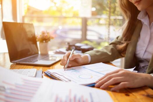 A young businesswoman is reviewing documents and their information to compile statistics and summarize annual results. The concept of reviewing annual turnover data from a collection of documents. photo