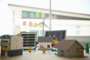 On desk of engineers lay model of house And solar panels to use in planning installation of solar panels to  house in order to get most cost effective energy from installing solar panels. photo