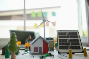 On desk of engineers lay model of house And solar panels to use in planning installation of solar panels to  house in order to get most cost effective energy from installing solar panels. photo