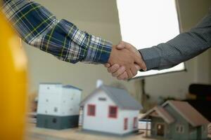 construction engineer joins hands with architect to congratulate housing project that architect team has designed and has been accepted by engineering team. concept of handshake for congratulations photo