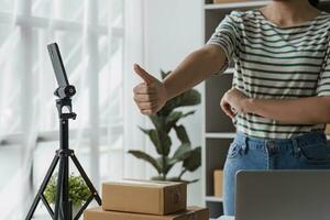 emprendedor de pequeñas empresas pyme autónomo, retrato de mujer joven que trabaja en la oficina en casa, caja, teléfono inteligente, computadora portátil, en línea, marketing, empaque, entrega, b2b, pyme, concepto de comercio electrónico. foto