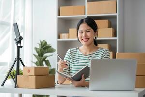 Starting Small business entrepreneur SME freelance, Portrait young woman working at home office, BOX, smartphone, laptop, online, marketing, packaging, delivery, b2b, SME, e-commerce concept. photo