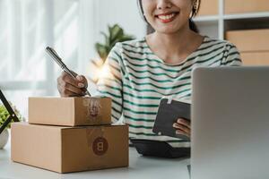 Starting Small business entrepreneur SME freelance, Portrait young woman working at home office, BOX, smartphone, laptop, online, marketing, packaging, delivery, b2b, SME, e-commerce concept. photo