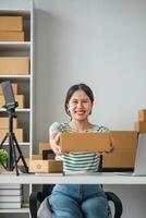 Starting Small business entrepreneur SME freelance, Portrait young woman working at home office, BOX, smartphone, laptop, online, marketing, packaging, delivery, b2b, SME, e-commerce concept. photo