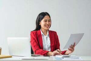 Cheerful business lady working on laptop in office, Asian happy beautiful businesswoman in formal suit work in workplace. Attractive female employee office worker smile. photo